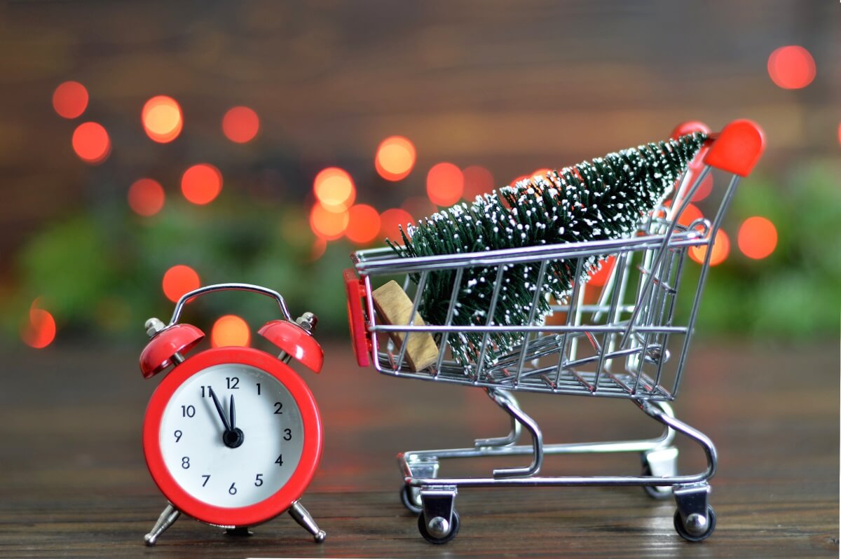a clock and little cart with a christmas tree in it