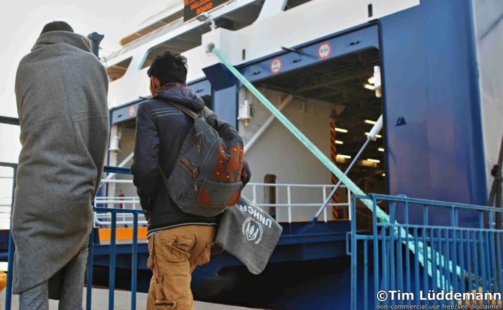 Two refugees wait to be able to enter the ferry in the port of Chios