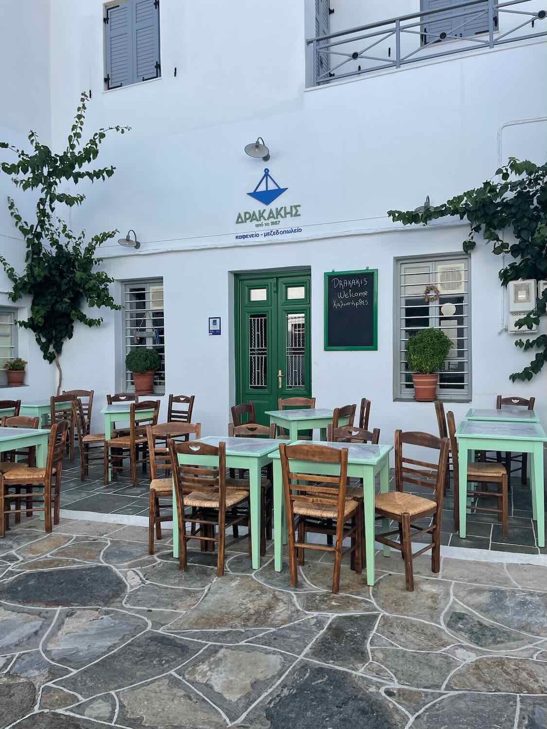 A cozy outdoor caf&eacute; in Sifnos with mint green chairs and wooden tables, inviting visitors to relax and dine.