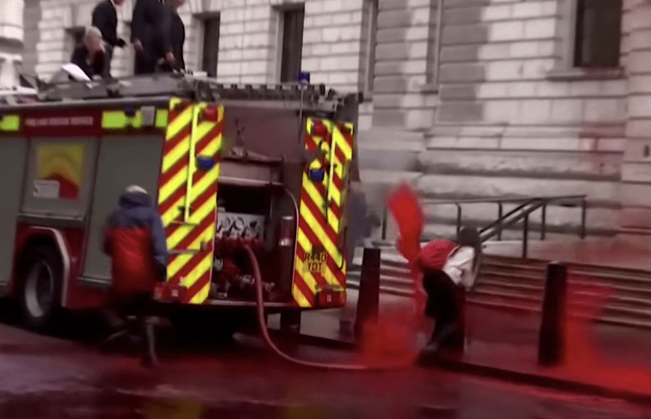 Through the streets with signs. Climate Protesters Lose Control of Fake Blood Hose in