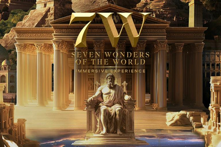 Golden letters "7W Seven Wonders of the World Immersive Experience" over a statue and ancient architecture.