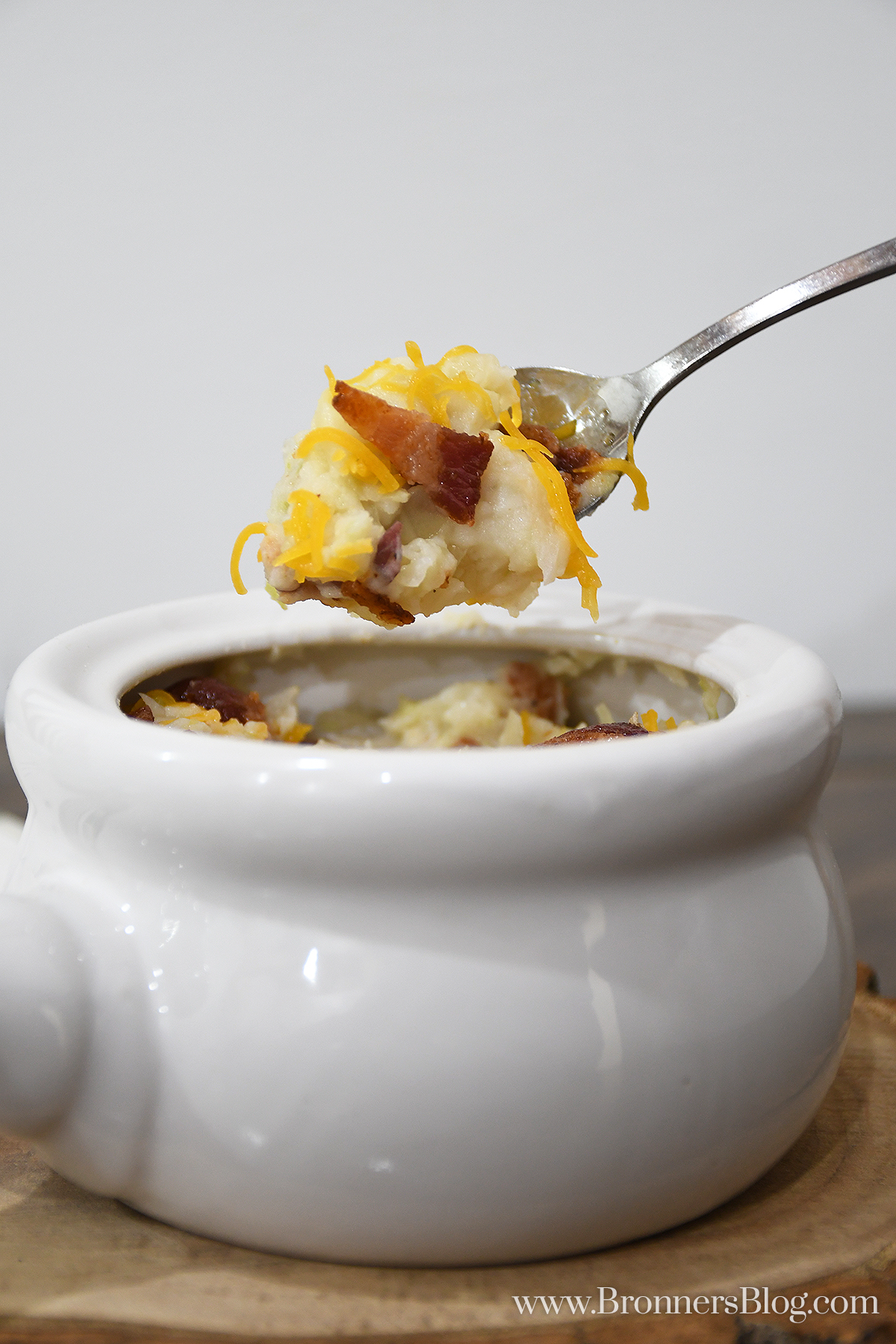 closeup of colcannon in white ceramic bowl with spoonful of colcannon held just above the bowl
