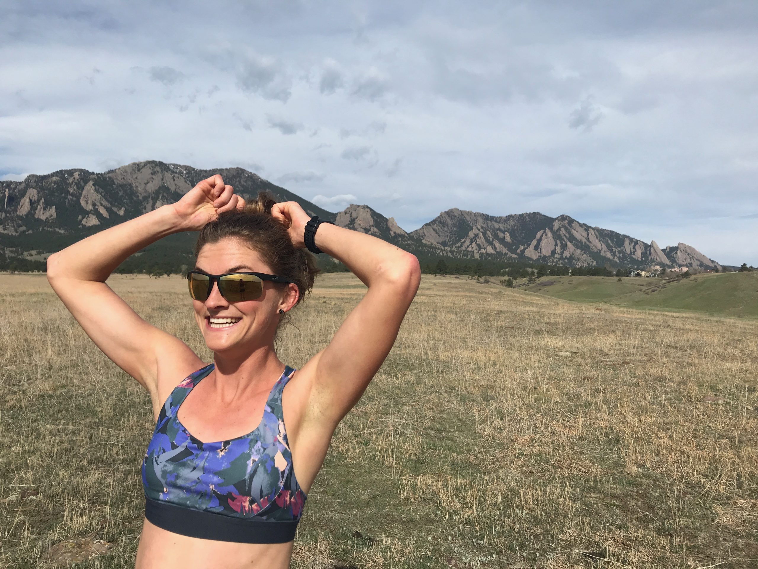Ultrarunner Clare Gallagher standing in a large meadow with mountains in the background.
