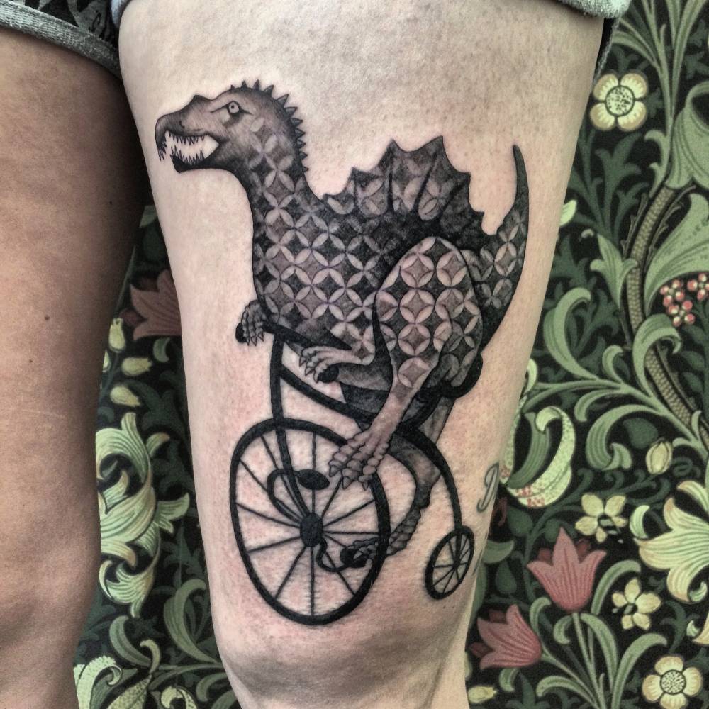 Patterned Dinosaur On A Bike Tattoo On The Left Thigh. 1000_x_1000_jpg