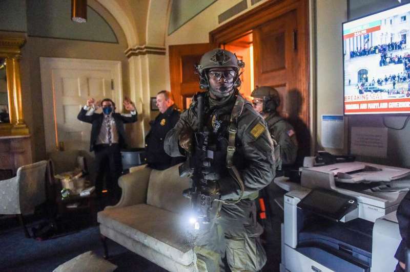 A Congress staffer holds his hands up while Capitol Police Swat team check everyone in the room as they secure the floor of Trump supporters in Washington, DC on January 6, 2021. Source: Photo: Olivier Douliery, AFP Via Getty Images.


