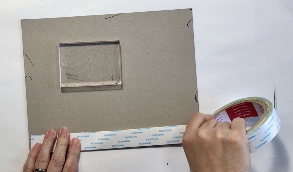 Photo showing the 1 inch Scor-tape used to adhere the scrapbook paper to the book board for today's How to Make an Exploding Busted Canvas project.