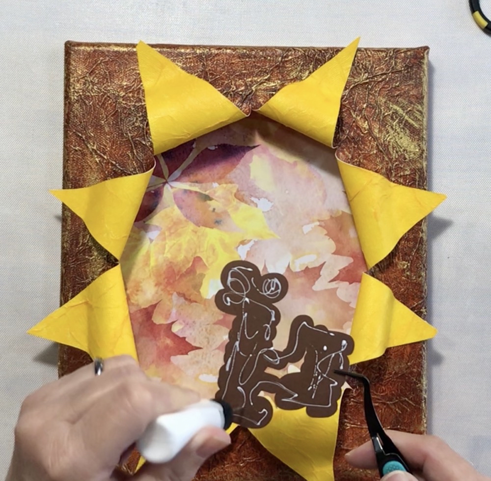 Photo showing the application of art glitter glue to the back of the Hello Fall sentiment used in today's project.