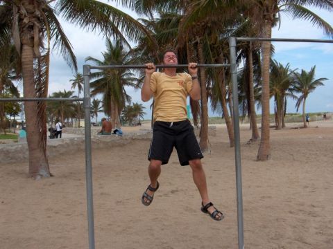 Man doing pull-ups on beach