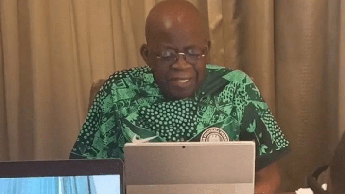 Tinubu looking at a device