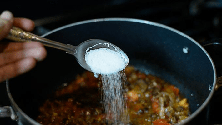 someone adding salt to food