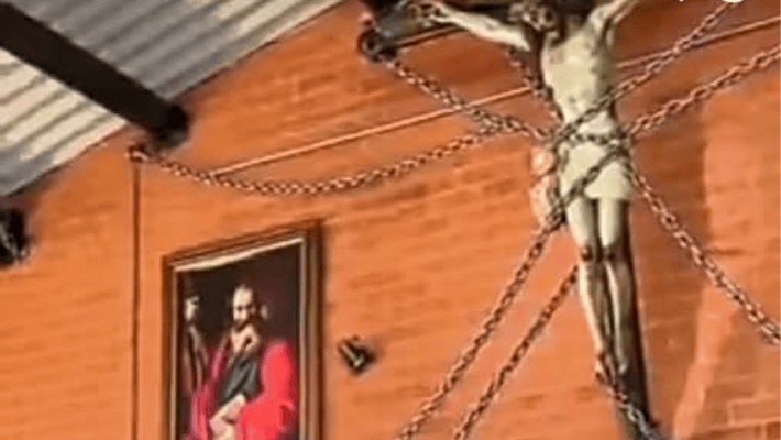 Image of the crucifixion of Jesus secured to a church wall with chains