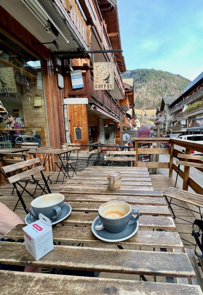 Sitting outside Satellite coffee looking down the street towards the mountains; two empty coffee mugs on a wooden table.