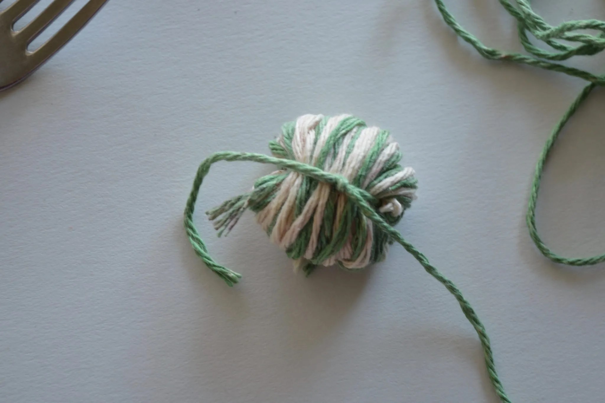An unfinished yarn pom pom ready to be cut and shaped.