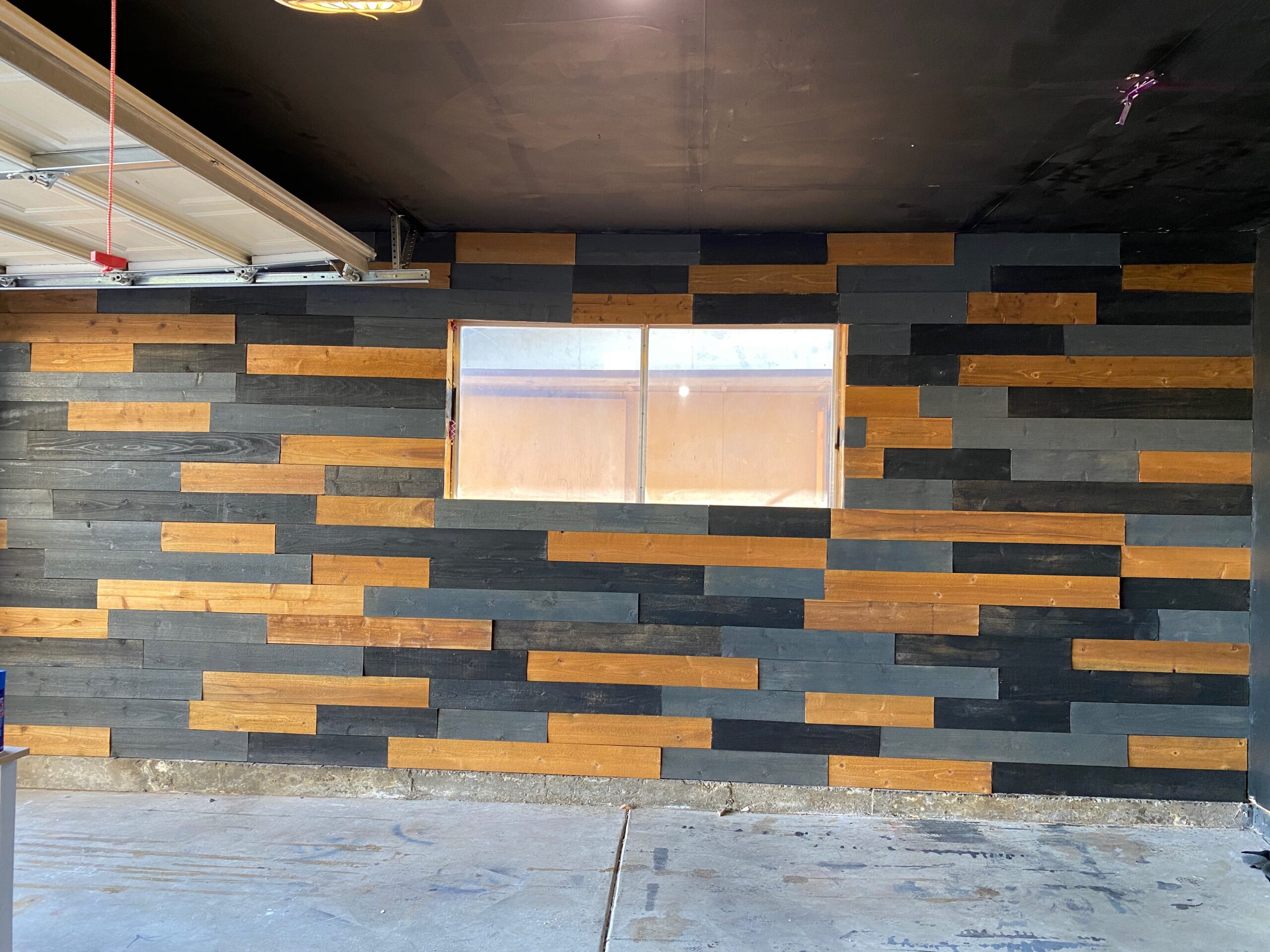 A wood accent wall with varying shades of tan, black, and grey