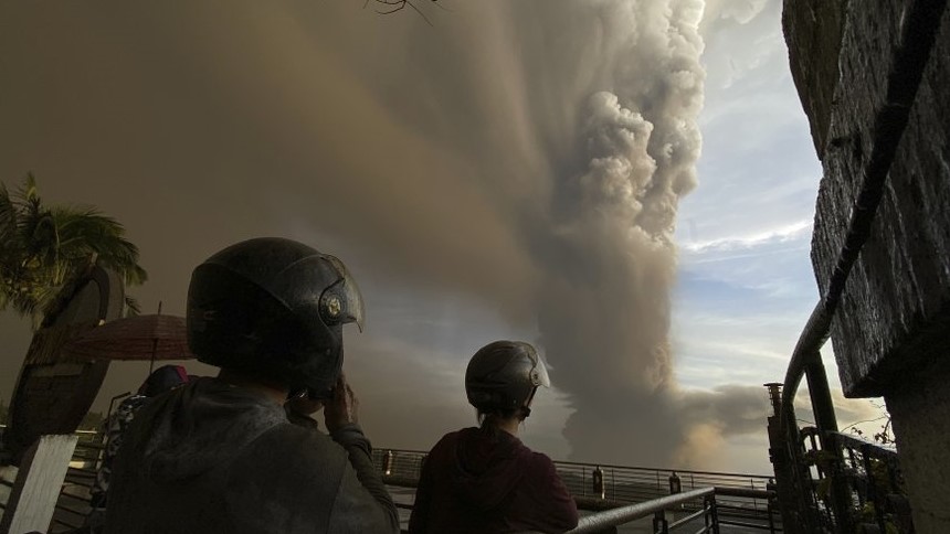 In this Jan. 12, 2020, photo, people watch plumes of smoke and ash rise from as Taal volcano erupts in Tagaytay, Cavite province, outside Manila, Philippines. (AP Photo/Aaron Favila)