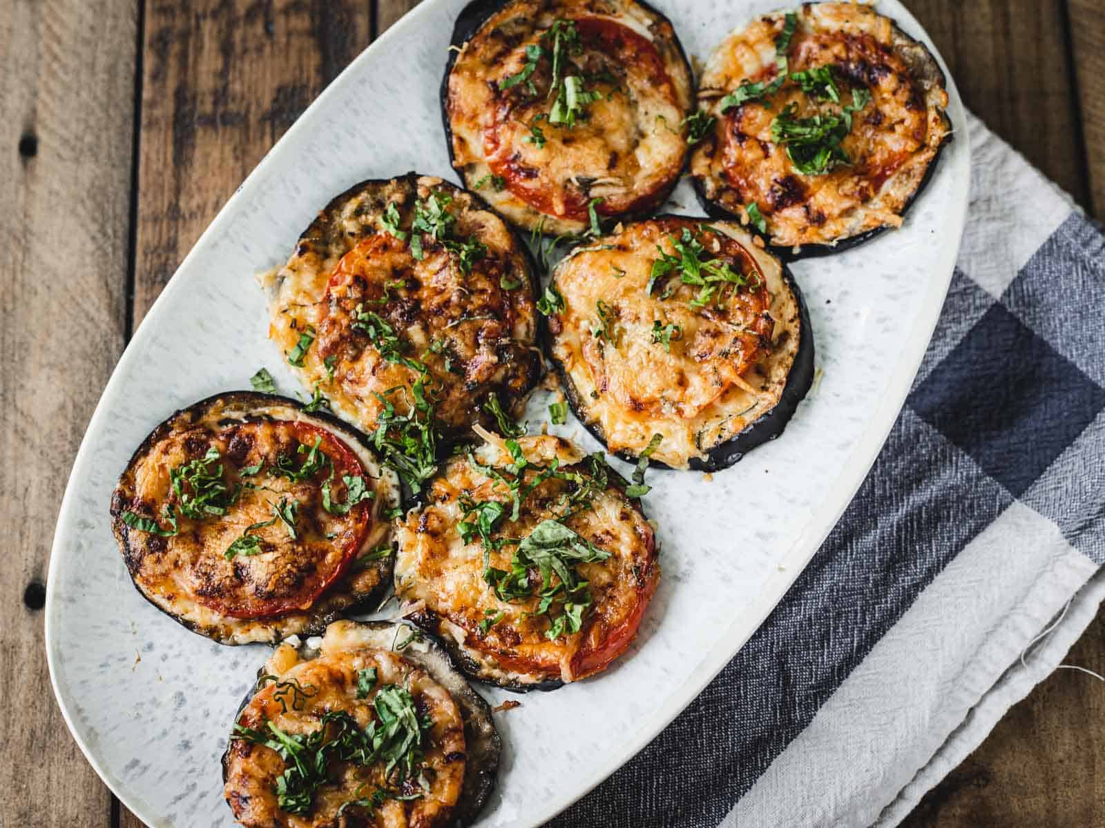 A plate of baked eggplant slices topped with melted cheese and garnished with herbs, ready to serve for dinner in just 30 minutes.