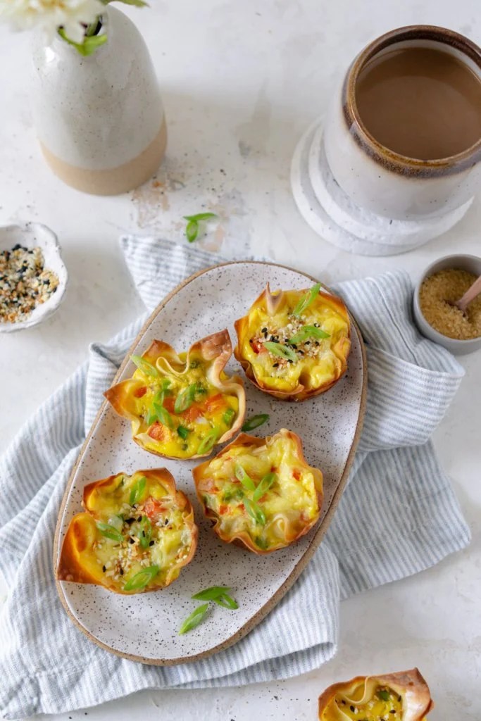 four egg bites on a white plate with coffee and a vase