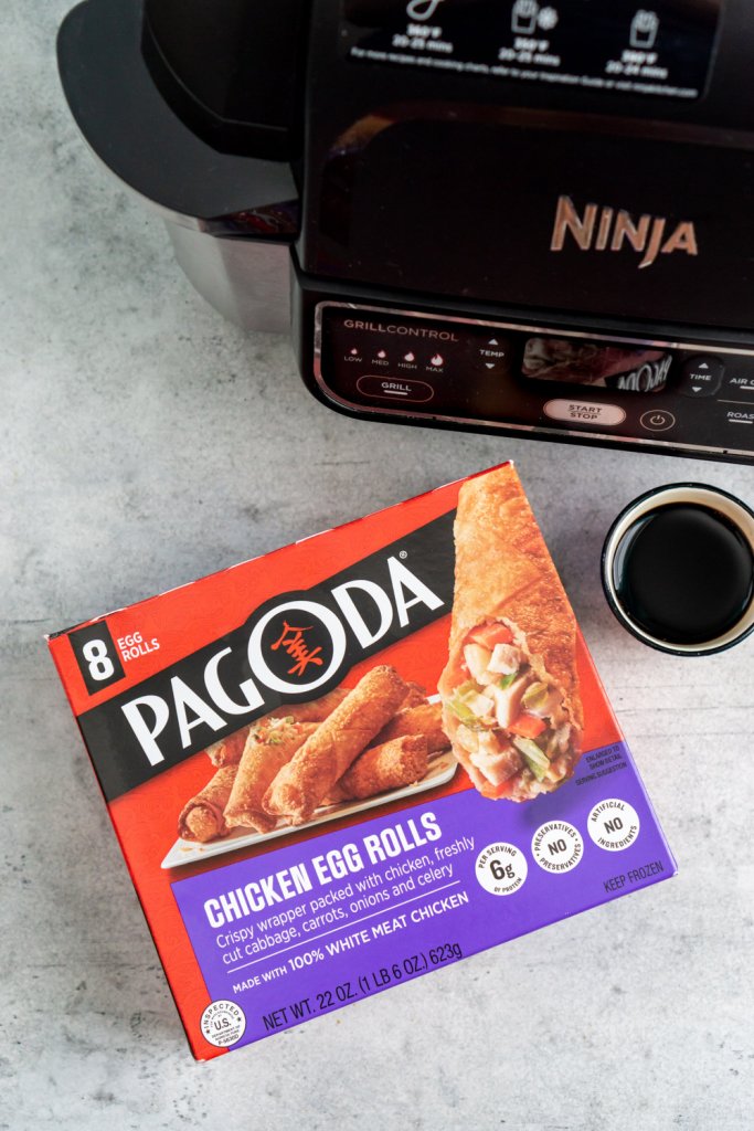 a box of frozen egg rolls next to an air fryer