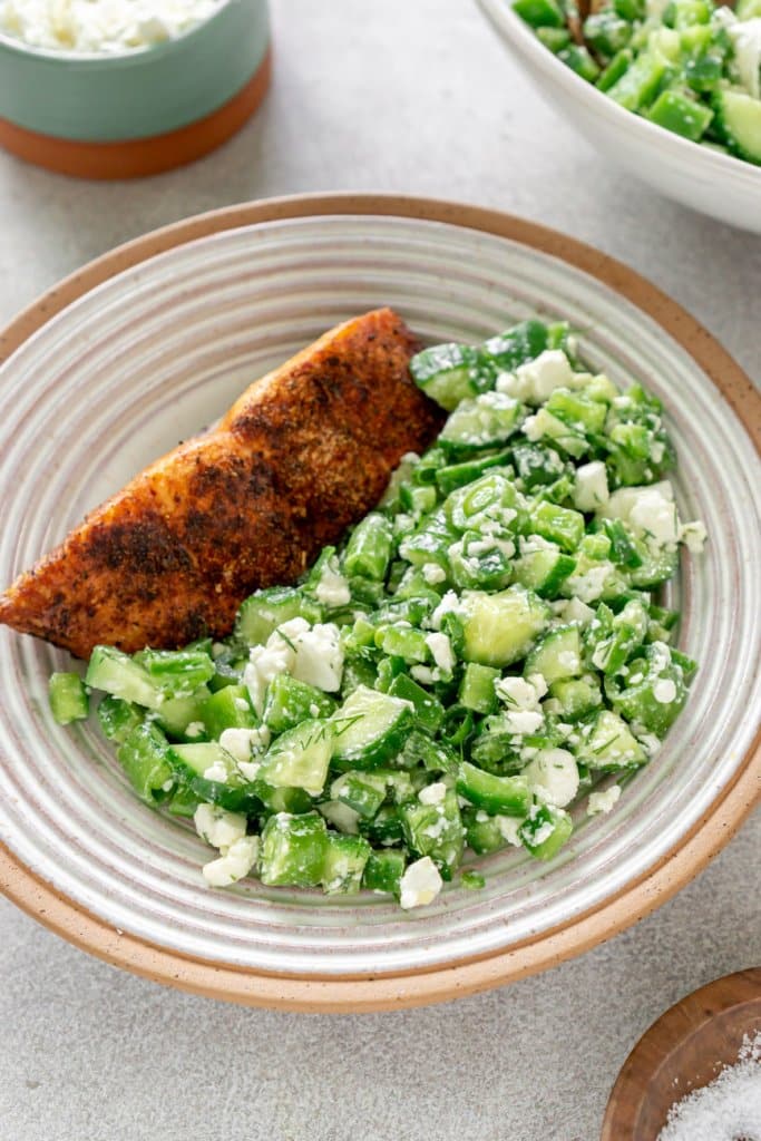 green vegetable salad in a serving bowl with salmon