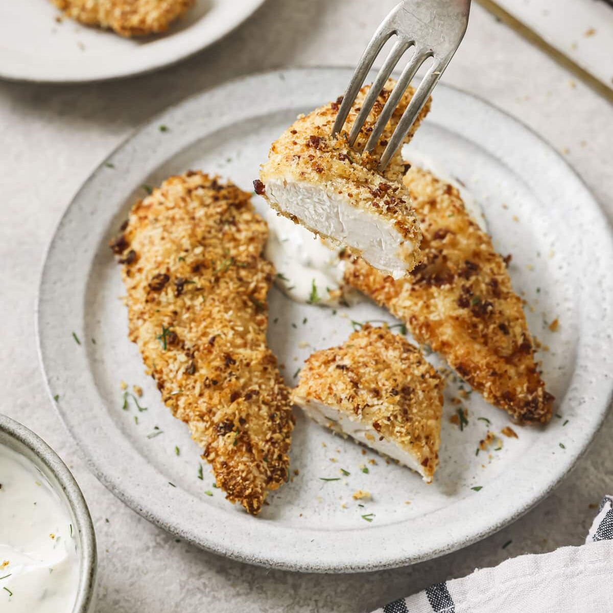 Crispy bacon ranch chicken cut on a plate with a fork lifting a piece up.