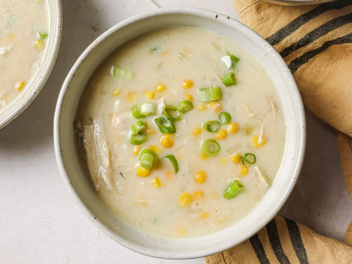 chicken corn soup in a bowl with a spoon taking a bite out.