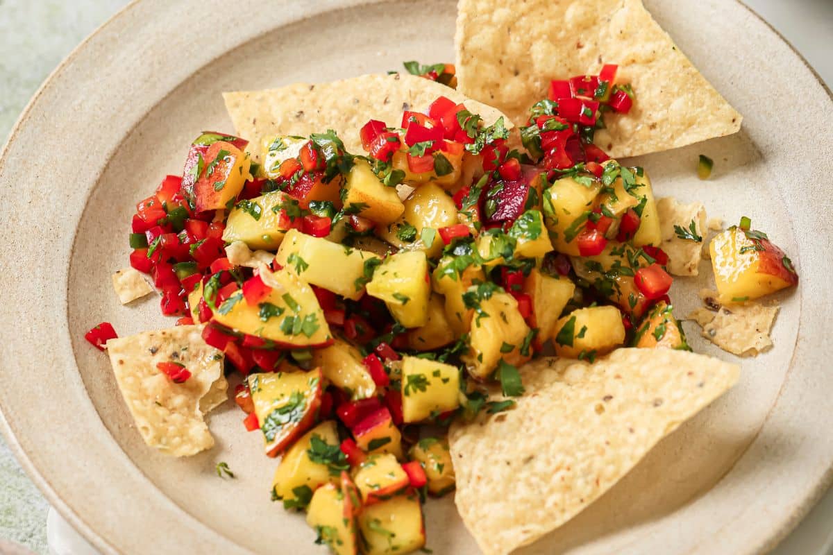A plate of tortilla chips topped with fresh peach salsa. 