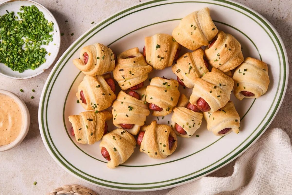 A plate full of air fryer pigs in a blanket with a side of homemade queso dip.