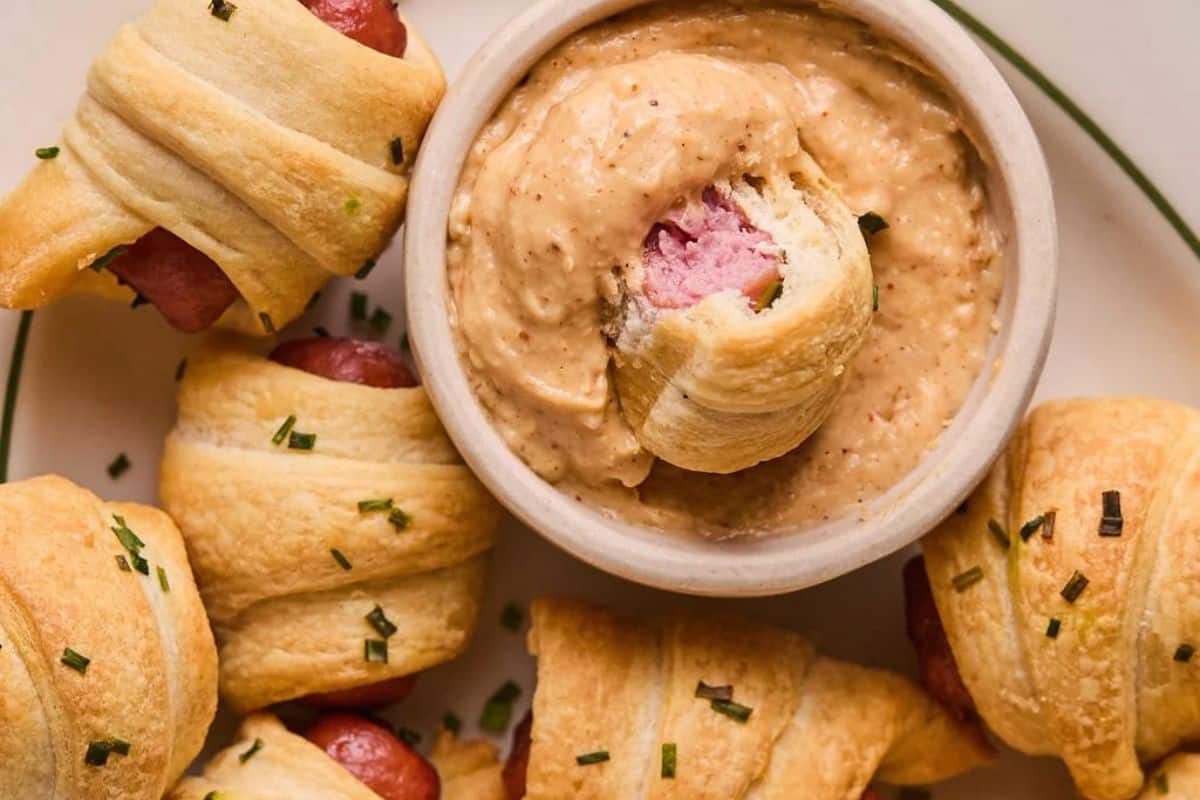A plate full of air fryer pigs in a blanket with a side of homemade queso dip.