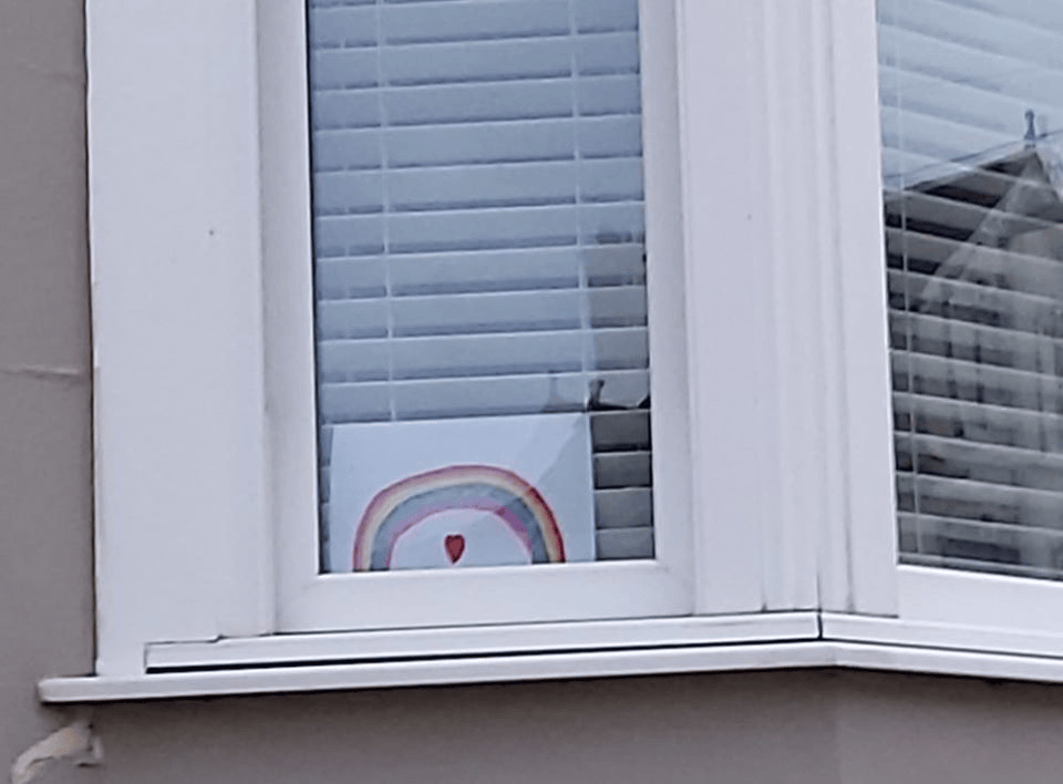 A small rainbow in a window with a heart in the window