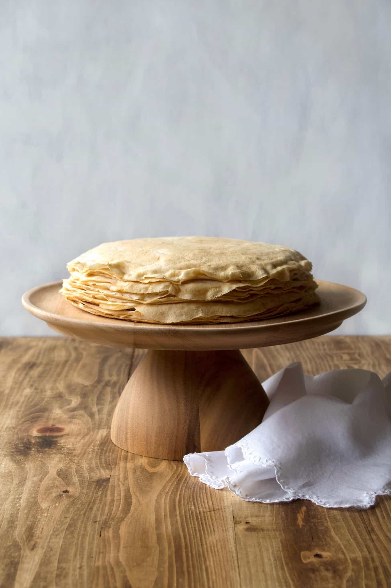 Coconut whipped cream sandwiched between layers of delicious crêpes, then topped with rich homemade dulce de leche! Whether you call it gâteau de crêpes, mille crêpe, or crepe cake, this is a beautiful and impressive dessert! #french #crepecake #crepes #pancakes #gateau #millecrepe #dulcedeleche #coconut #dairyfree #condensedmilk #caramel #cake