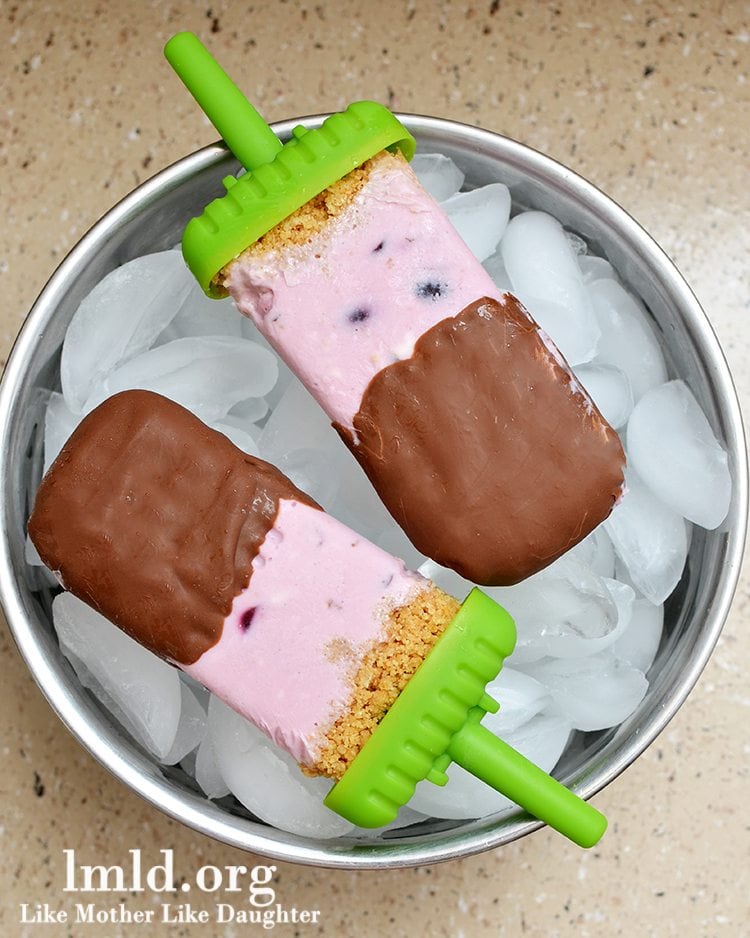 Front view of chocolate covered cherry cheesecake popsicles over ice.