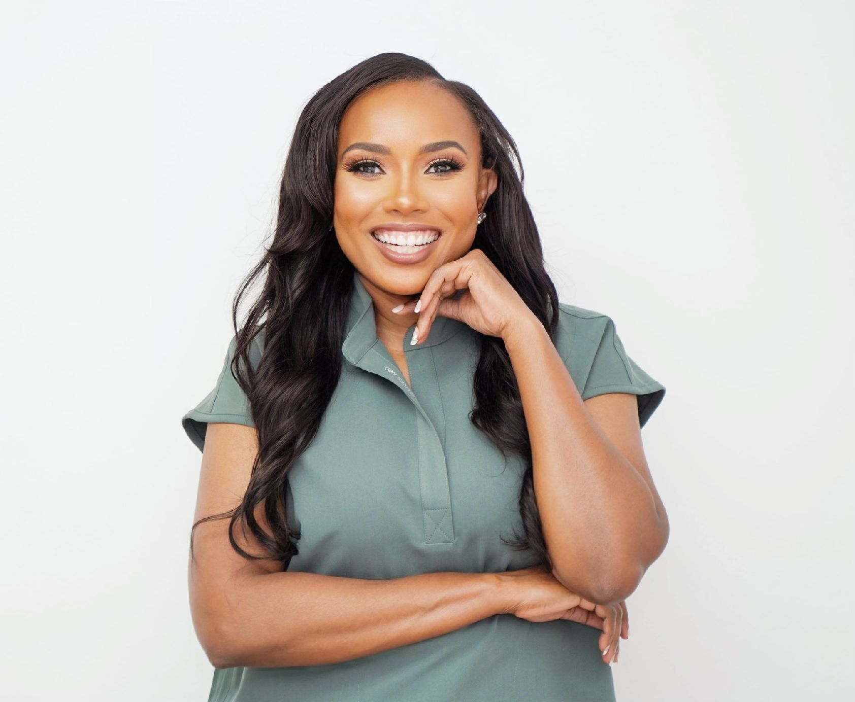 Stacy Phillips smiling with one arm folded and the other touching her face.