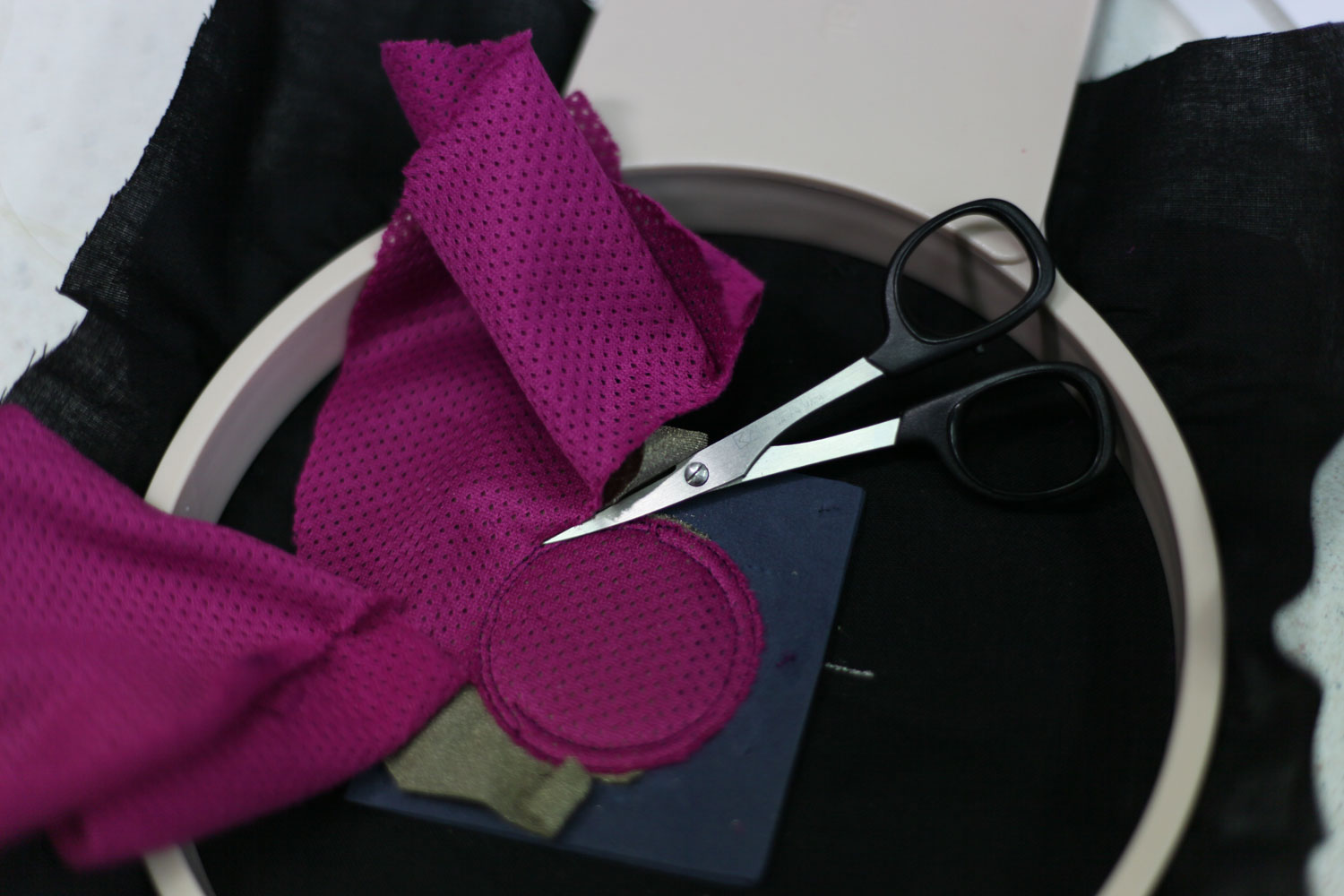 Place any fabric on top to insulate the conductive fabric. Cut away all the extra fabrics around the edge of the button.