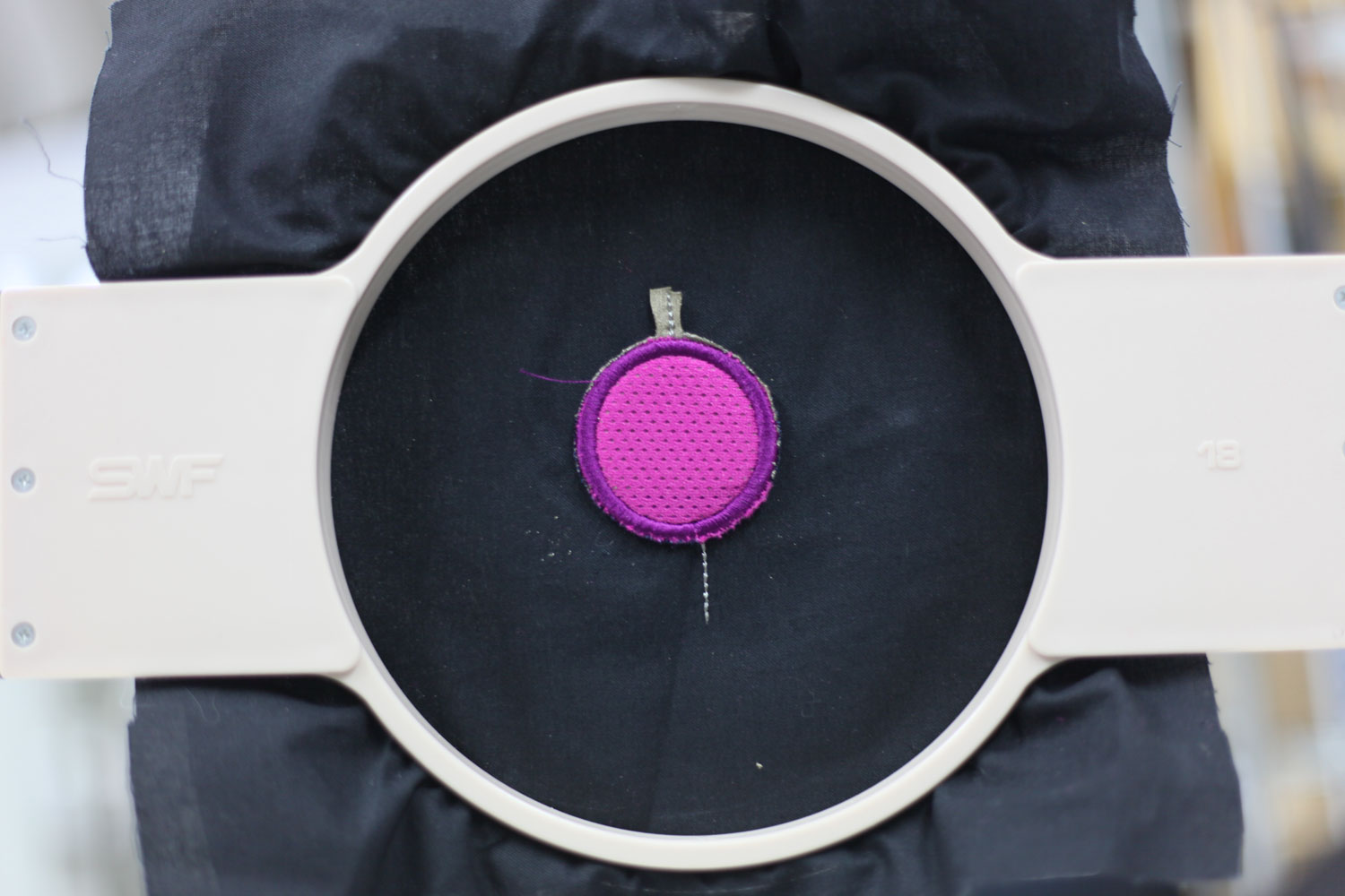 Embroidered push button with two connection points.