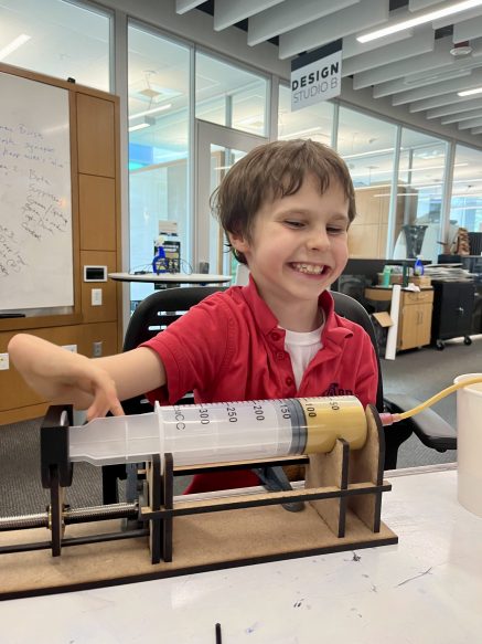 2022 TOM Makeathon need-knower, Hugh, testing out a self-feeding device made by students (Submitted photo)
