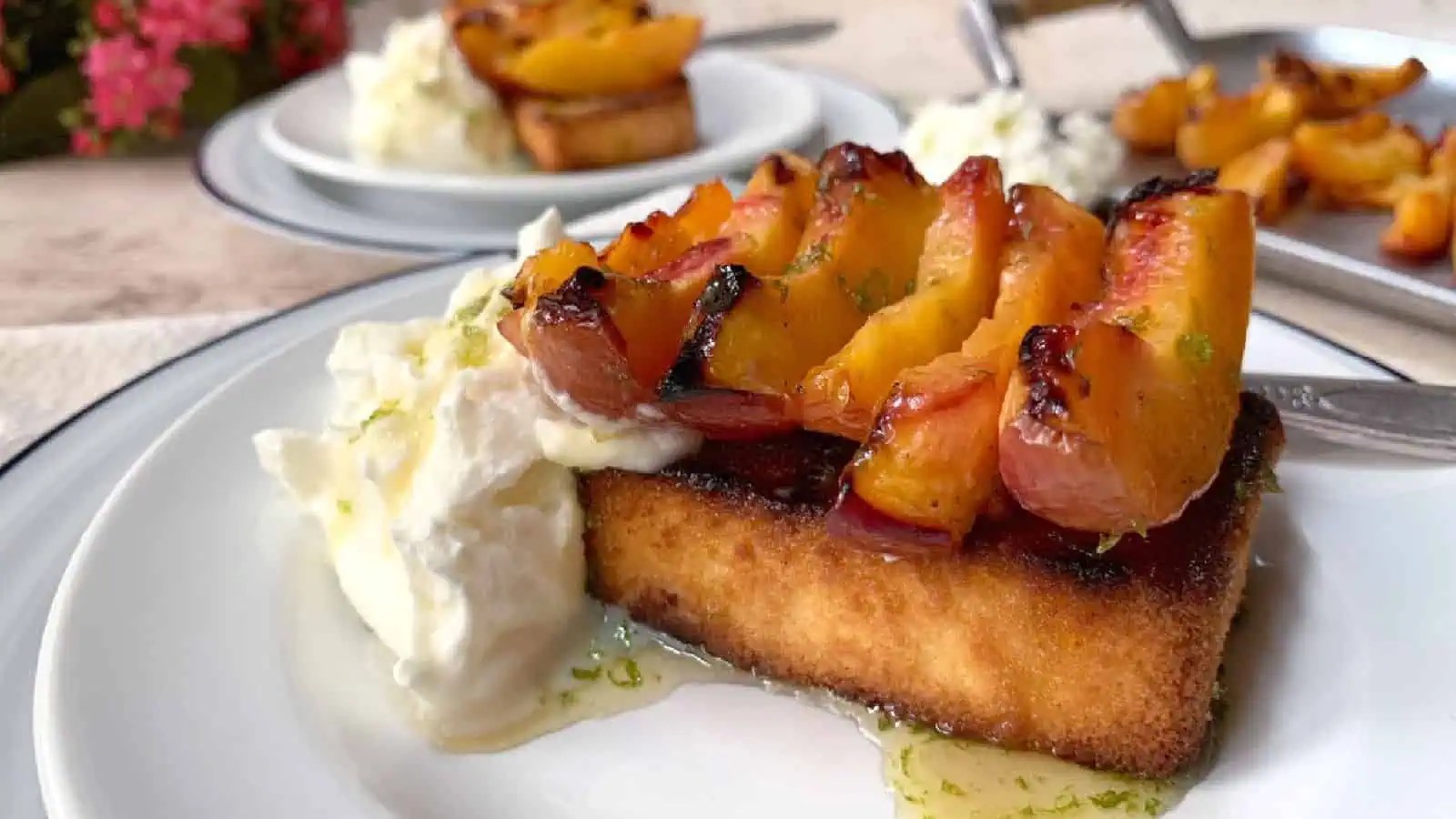 Grilled peaches on toast with a dollop of whipped cream on a white plate.