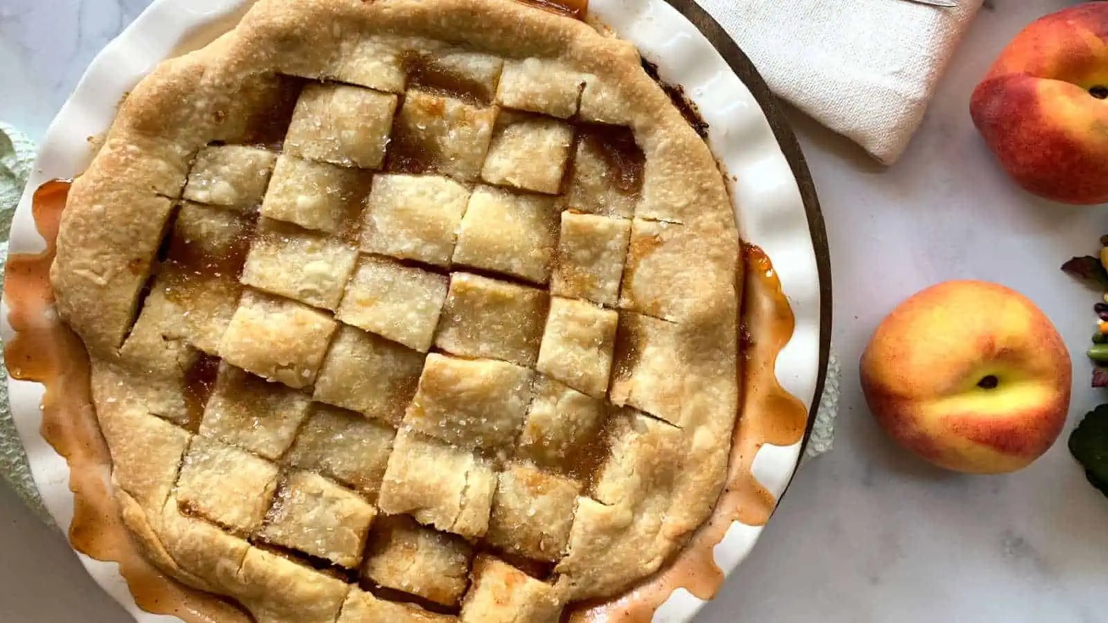 Freshly baked peach pandowdy pie with lattice crust on a kitchen counter.