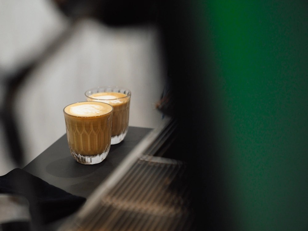 - Healthy Brew Hub Two milk-based coffee beverages in glasses next to an espresso machine.