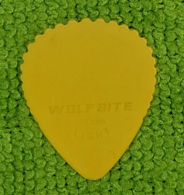 The Yellow "Wolfbite" .060mm Light Pick set against Green Background.