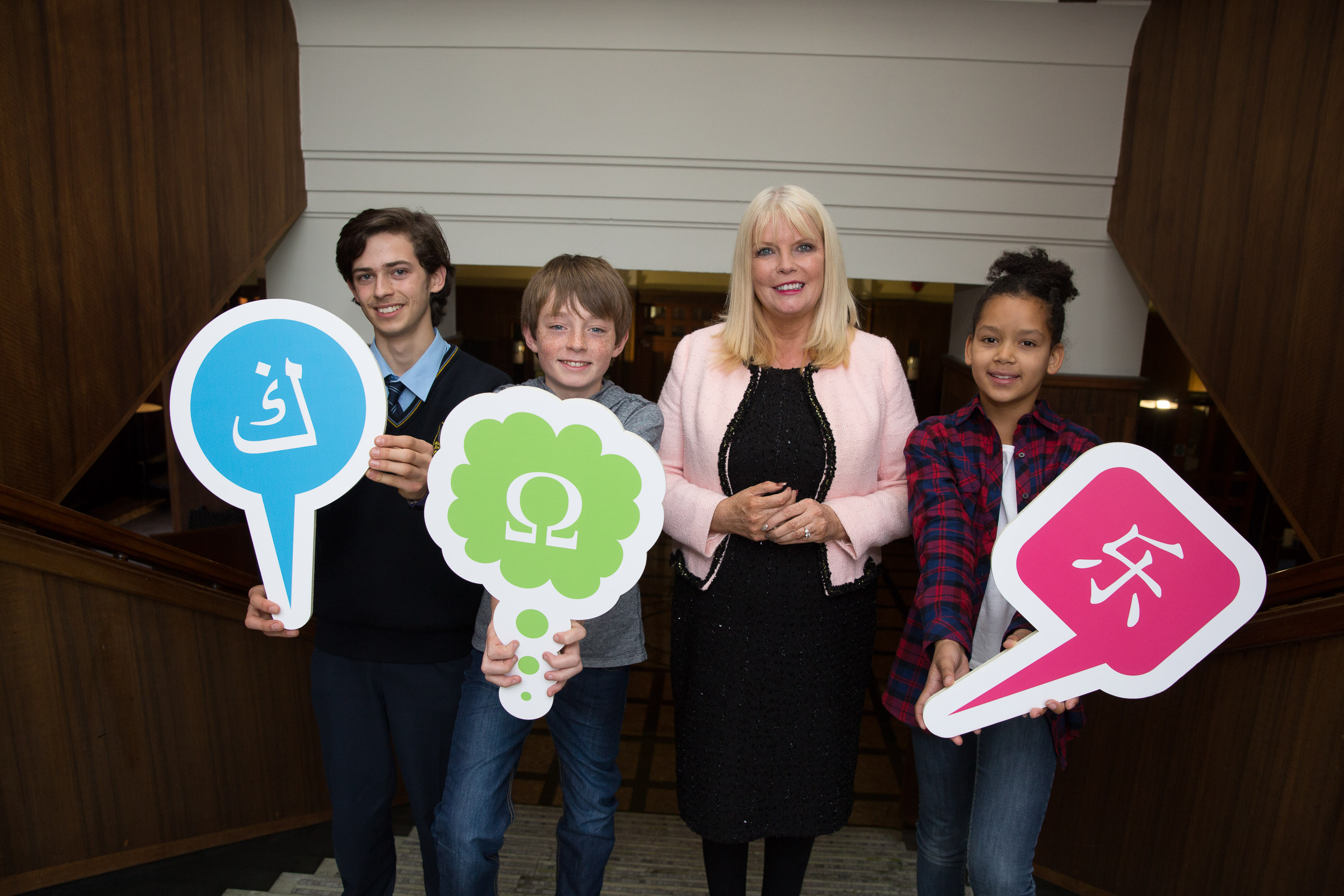 Photo of Mary Mitchell O'Connor with young students holding speech bubbles with colourful language icons