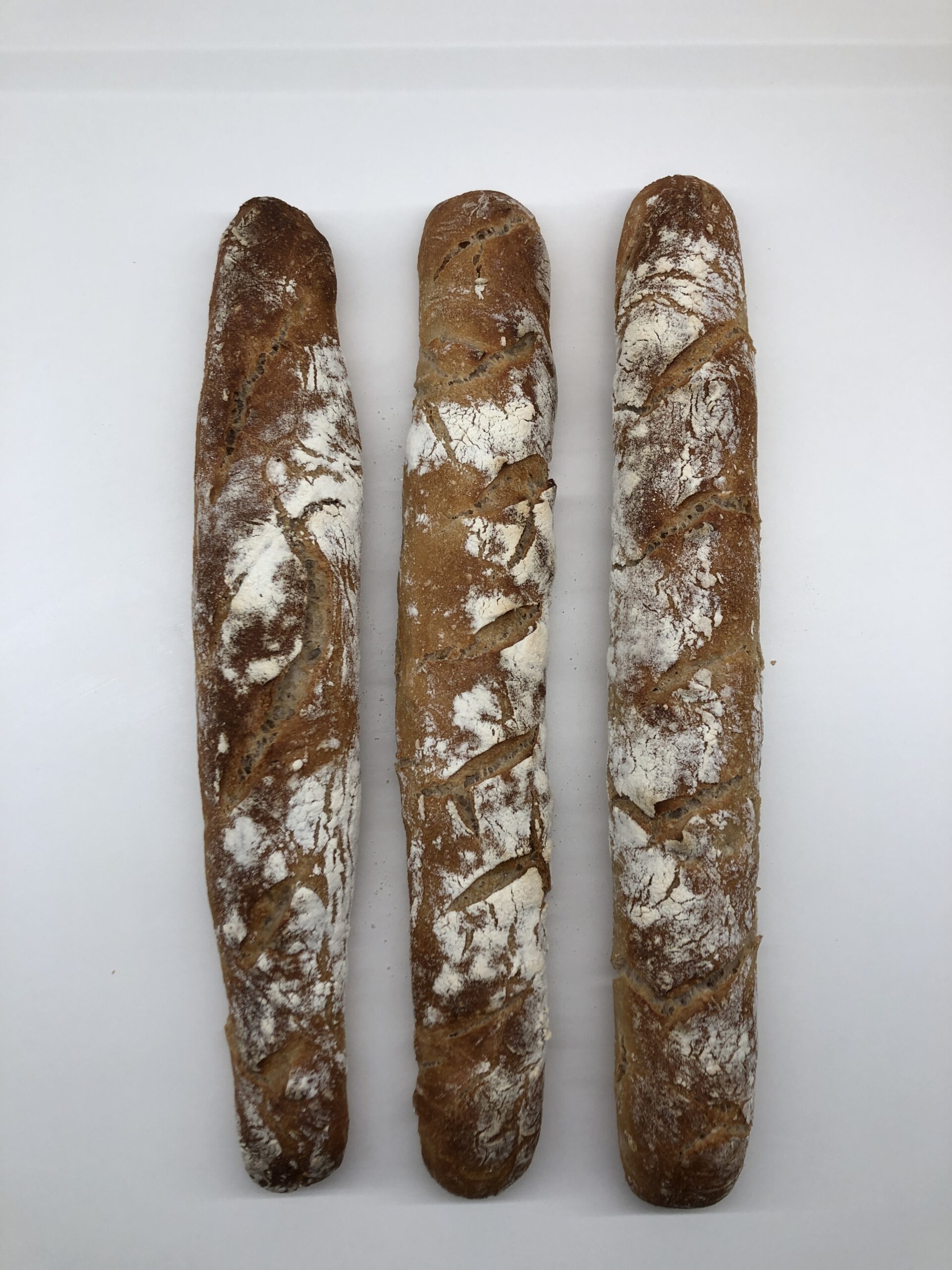 Drei dunkel gebackene Baguette liegen grade nebeineander