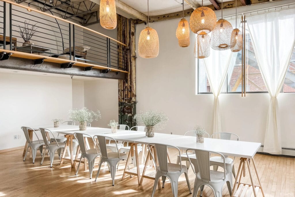 A sweet white table with vases of babies breath in a white room with rattan accents and big windows