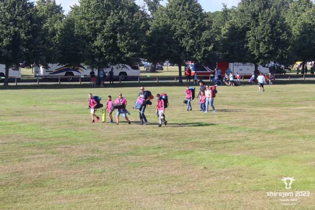 group of scouts carrying kit across a field 