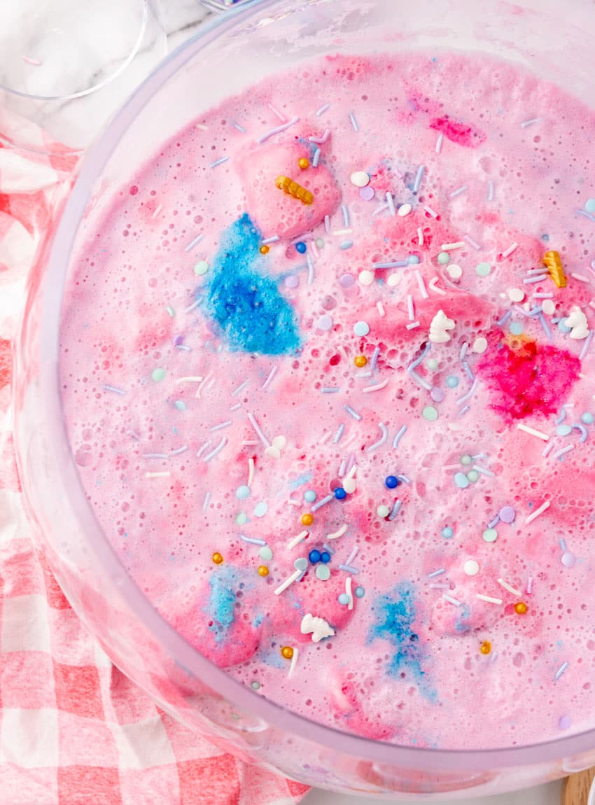 homemade unicorn punch with cotton candy in a glass punch bowl