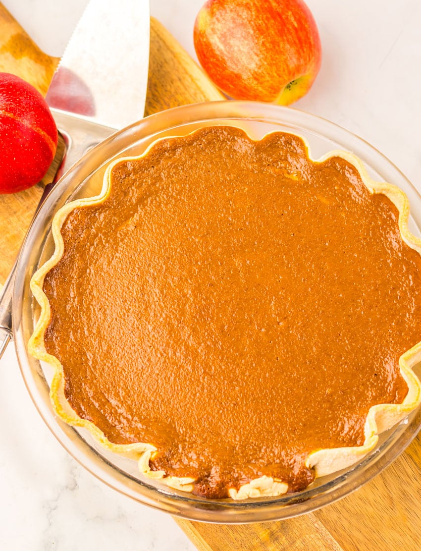 a baked apple butter pie cooling on a wooden cutting board