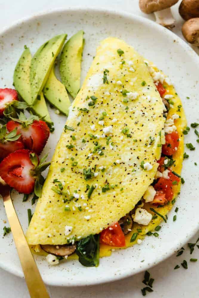 Savory breakfast omelets are so classic and my go to for a home run breakfast! Quick, easy, and delicious, this healthy breakfast option will leave you feeling full and satisfied! A cooked, finished omelet on a plate.