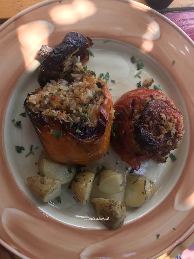 Tomato stuffed with rice and sides of baked potato