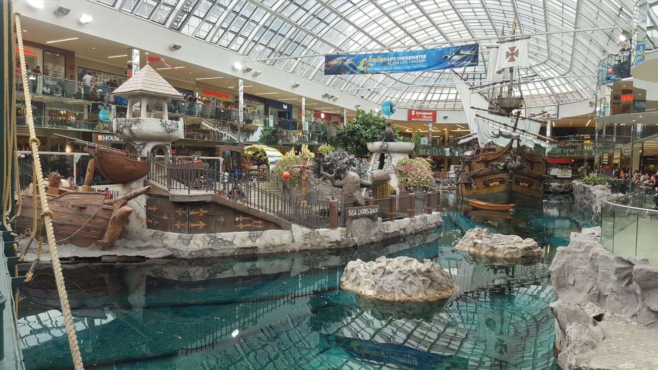 Clear blue water with ships and stores inside a large shopping complex in Edmonton.