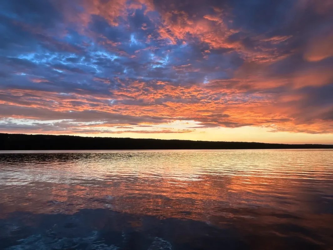 Colorful sunset sky reflecting over calm lake water.
