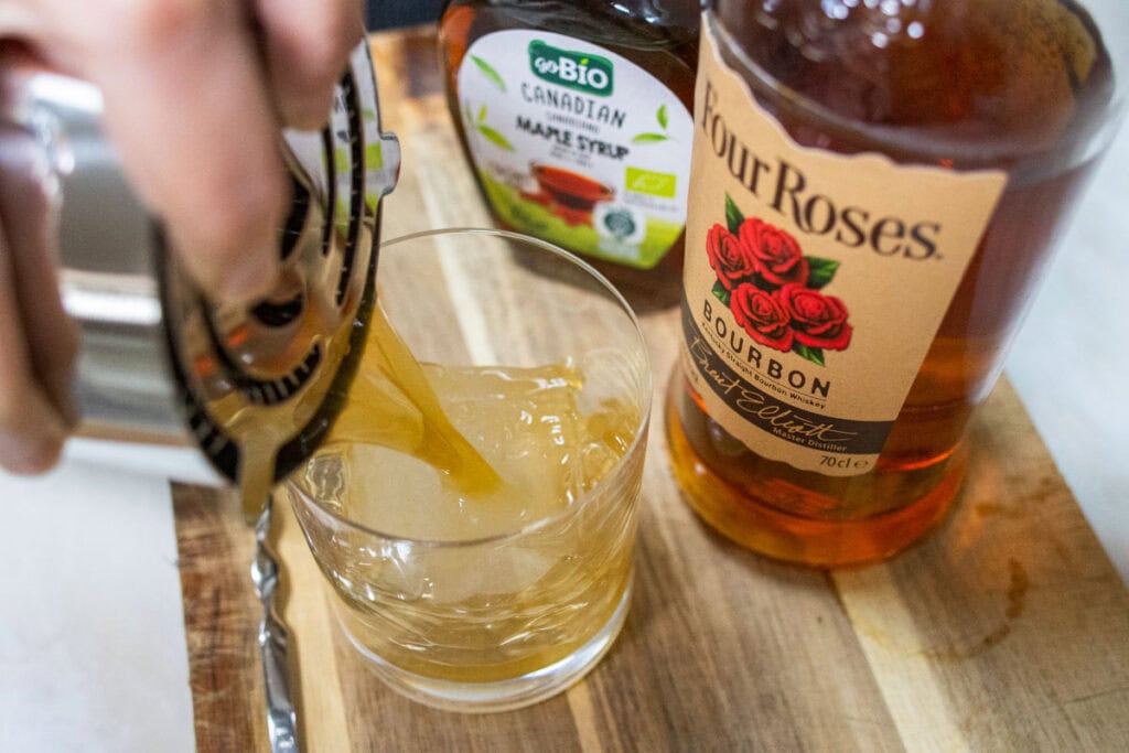 Straining Maple Bourbon Smash into Rocks Glass